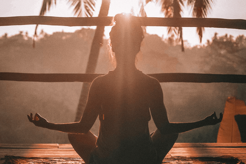 woman meditating with a view of palm trees
