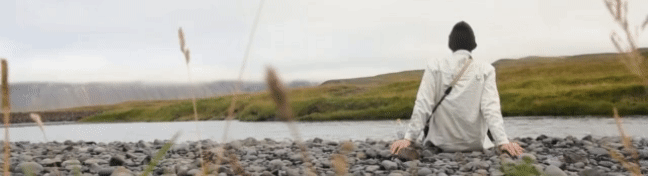 video of person sitting by a lake